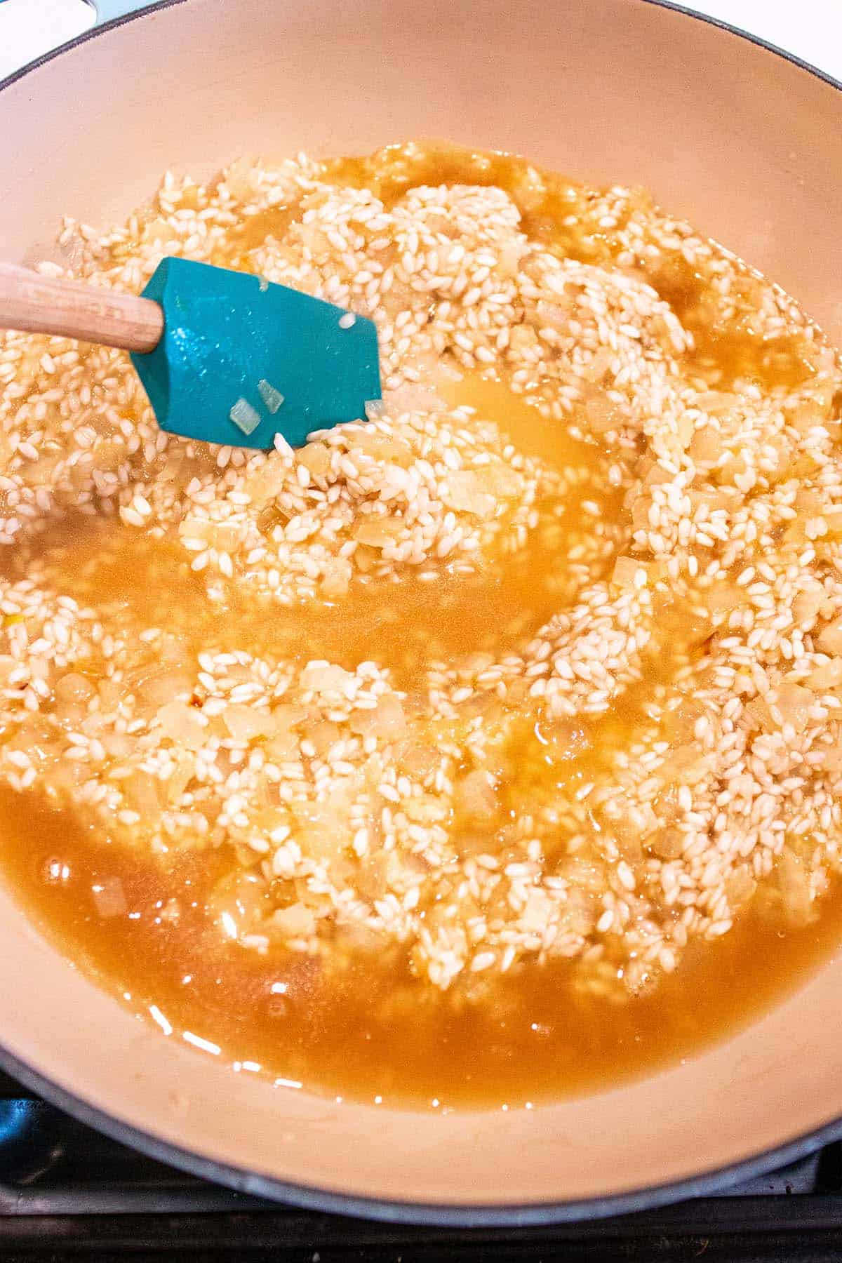 A spatula stirring rice in a vegetable stock.