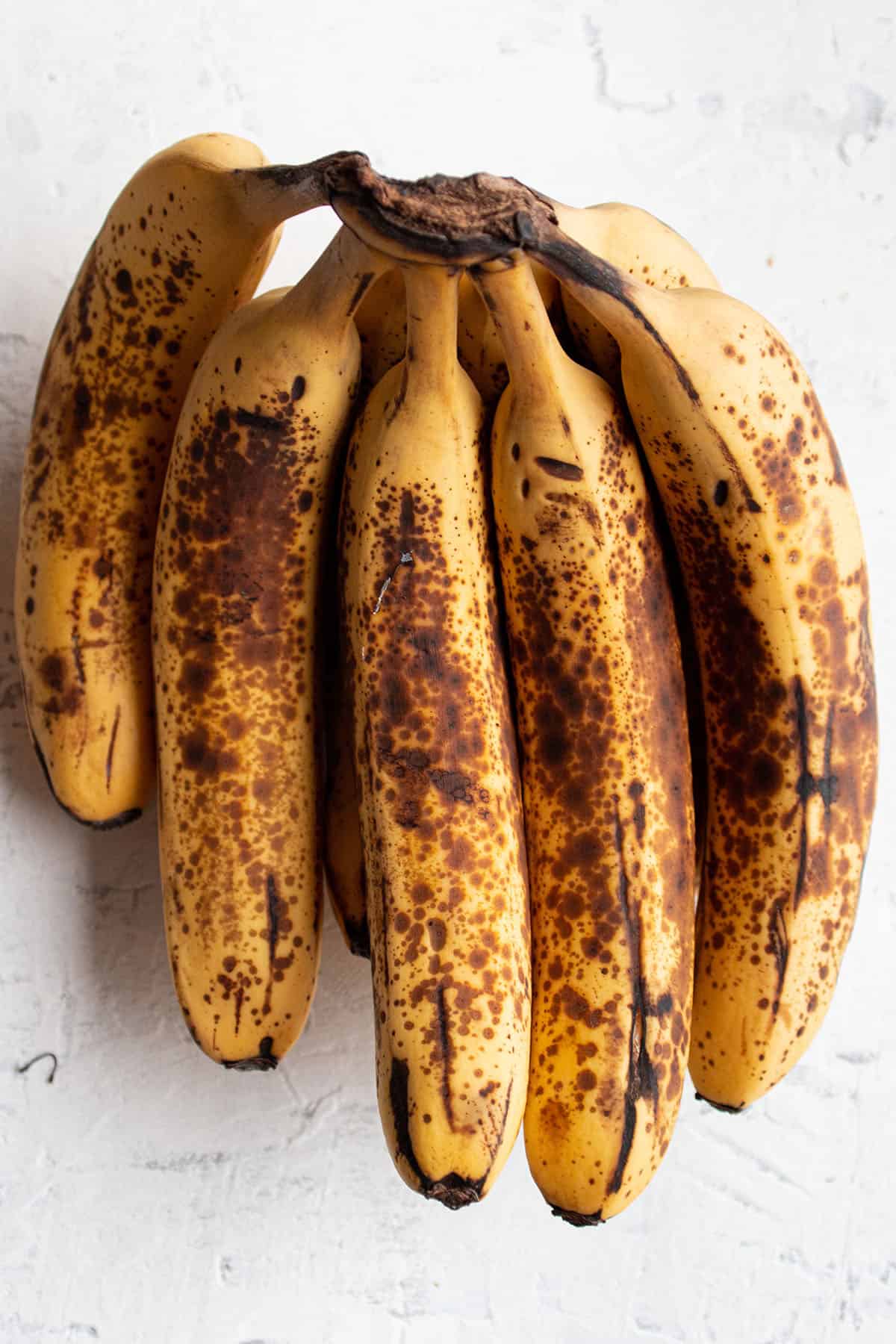 A bundle of overly ripe banana with brown speckles.
