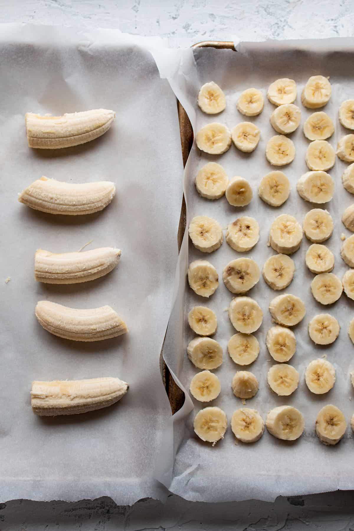 Two sheet pans with parchment and cut up bananas.