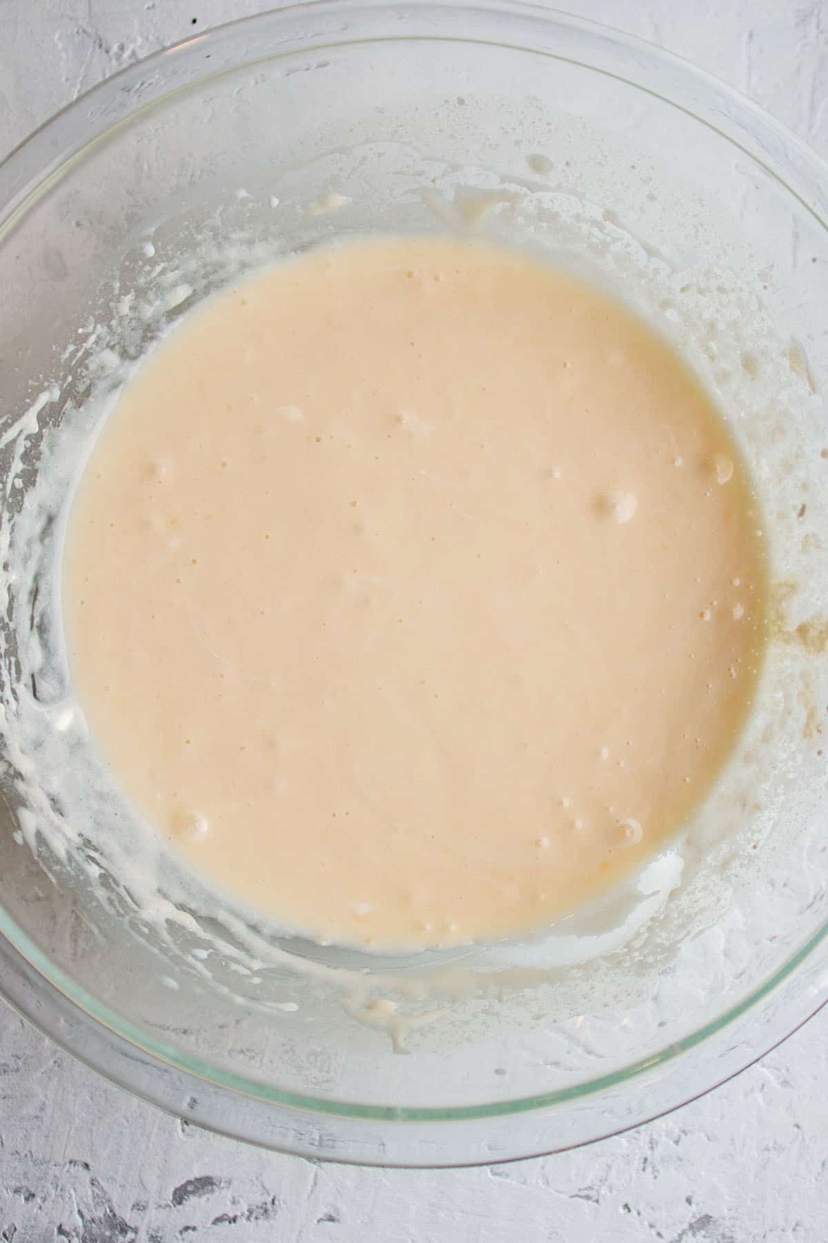 A glass bowl with a batter made with sourdough starter, sugar and eggs.