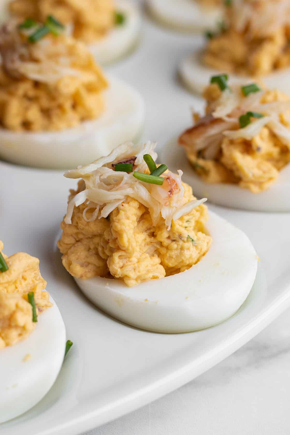 A plate with deviled eggs topped with fresh crab and chives. 