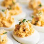 A plate with deviled eggs topped with shredded crab and freshly diced chives.