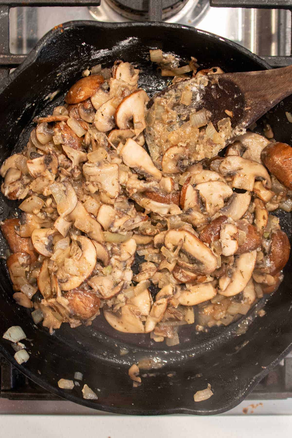 A cast iron skillet with mushrooms being cooked down.