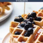 A stack of waffles with blueberries and syrup.