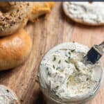 A board with a jar of cream cheese and bagels.