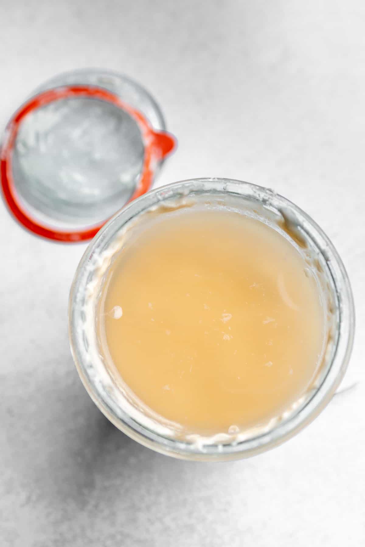 A glass jar with a sourdough starter and a lid with a rubber ring.