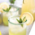 Two glasses with a lemonade, fresh mint leaves and lemon slices.
