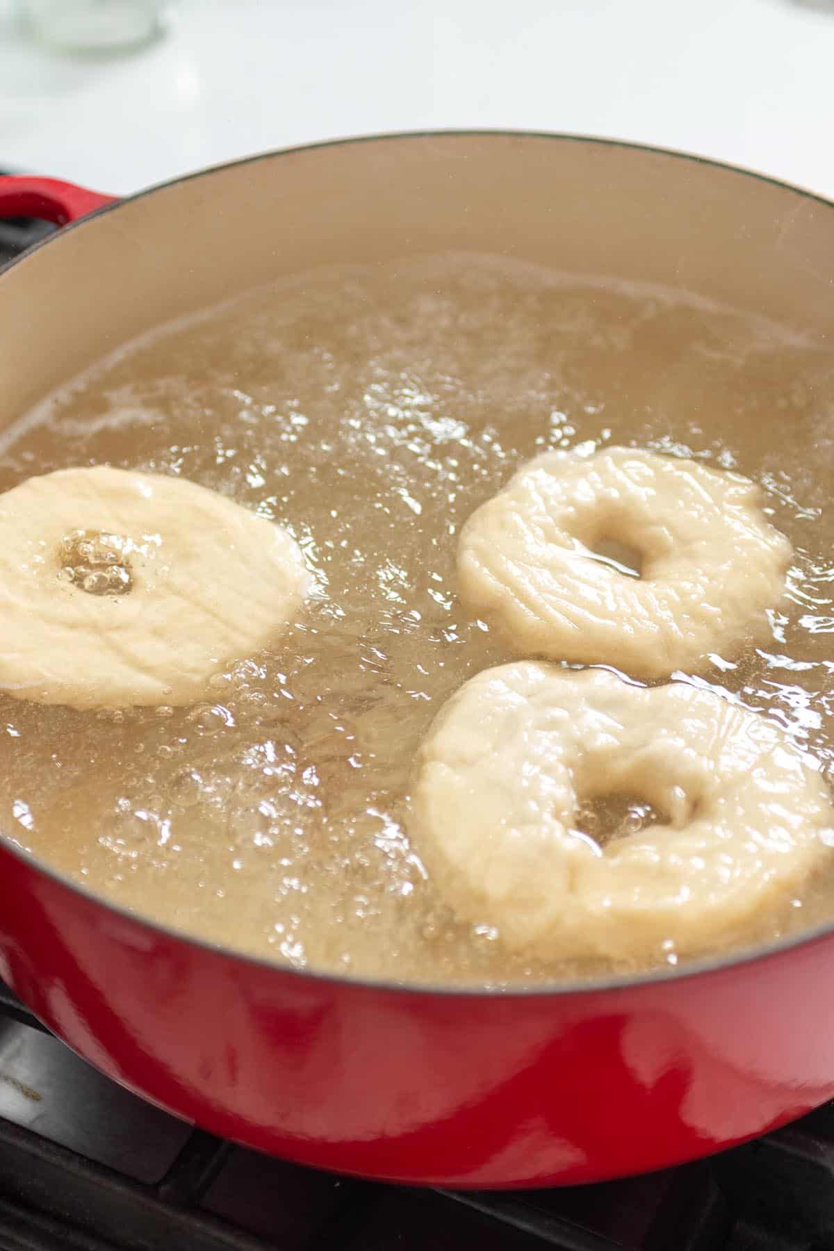 A large dutch oven with boiling water and bagels.