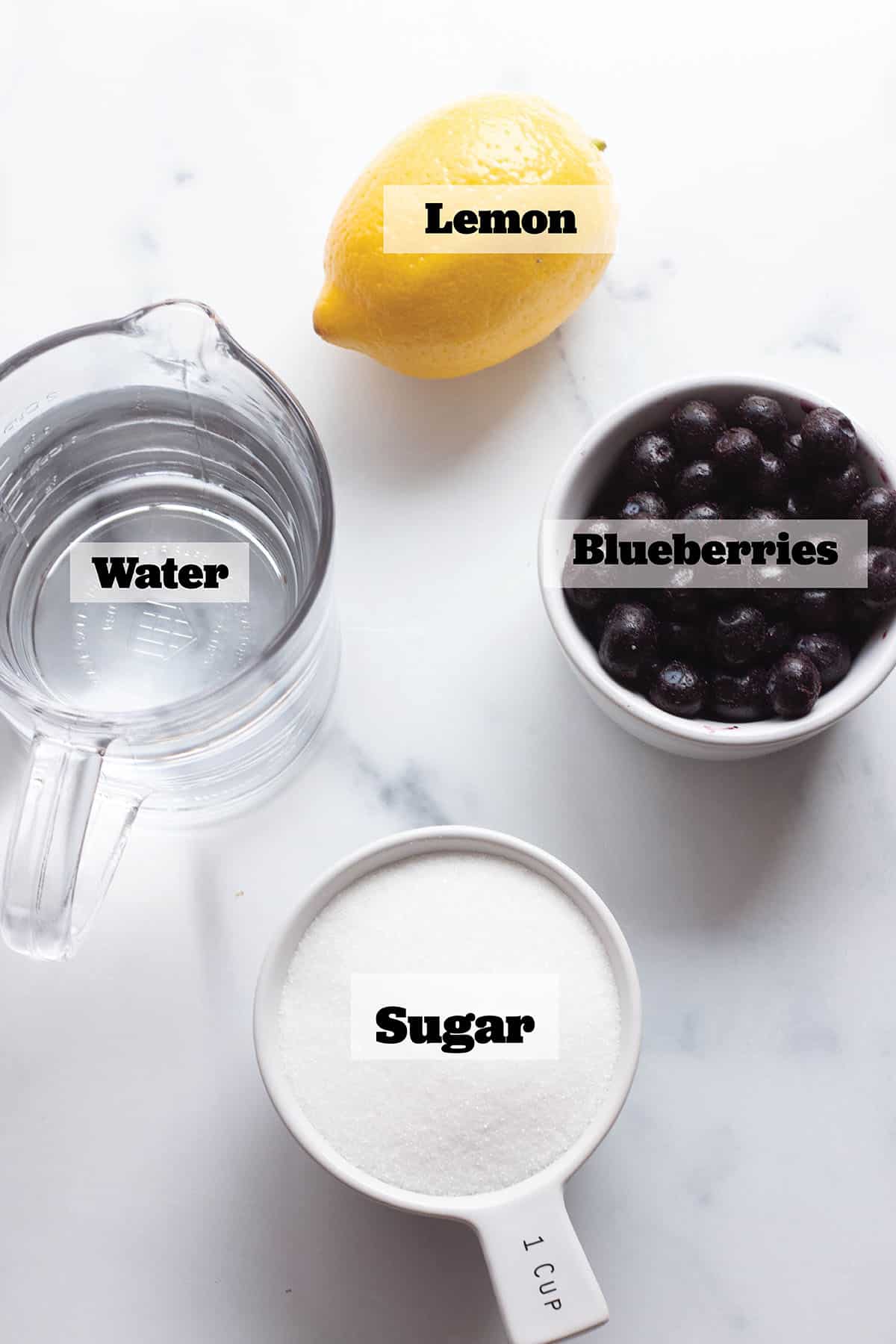 A cup of water, sugar, blueberries and a fresh lemon.