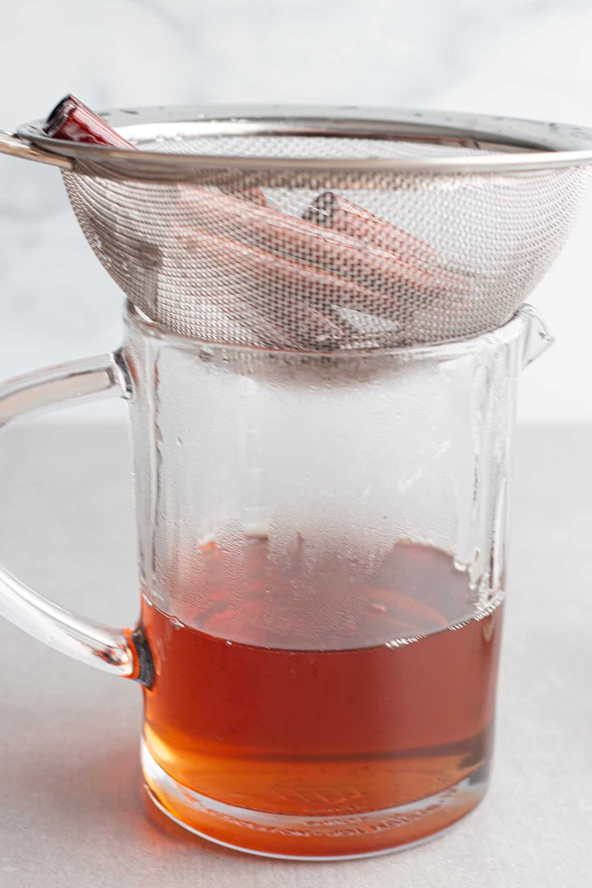 A liquid measuring cup with a fine mesh strainer on top.