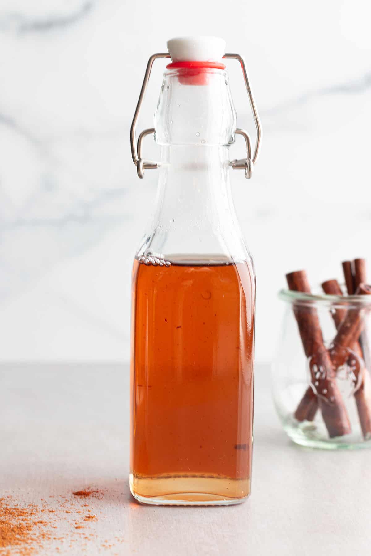 A flip lock bottle with a cinnamon syrup and a jar of cinnamon sticks. 