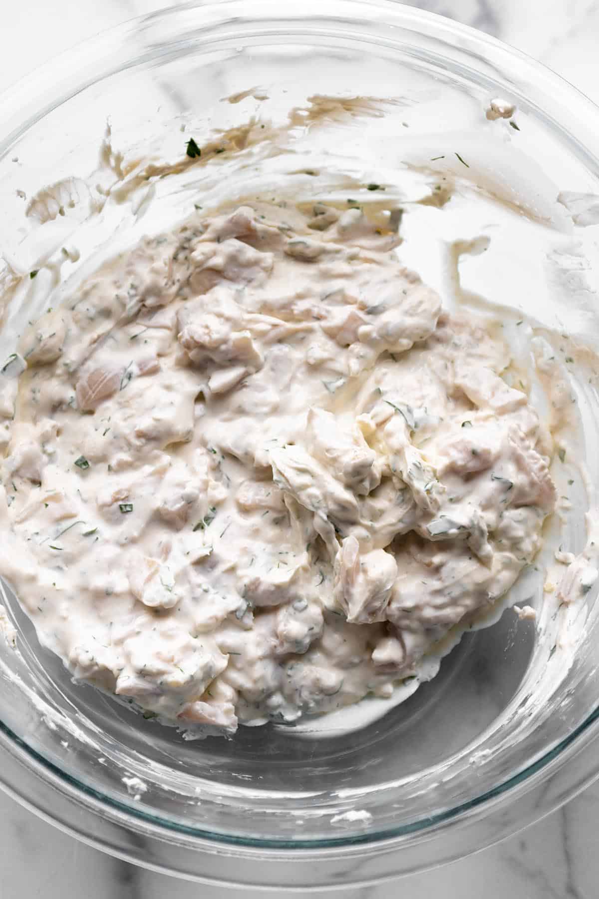 A bowl of cream cheese with herbs and fresh clams.