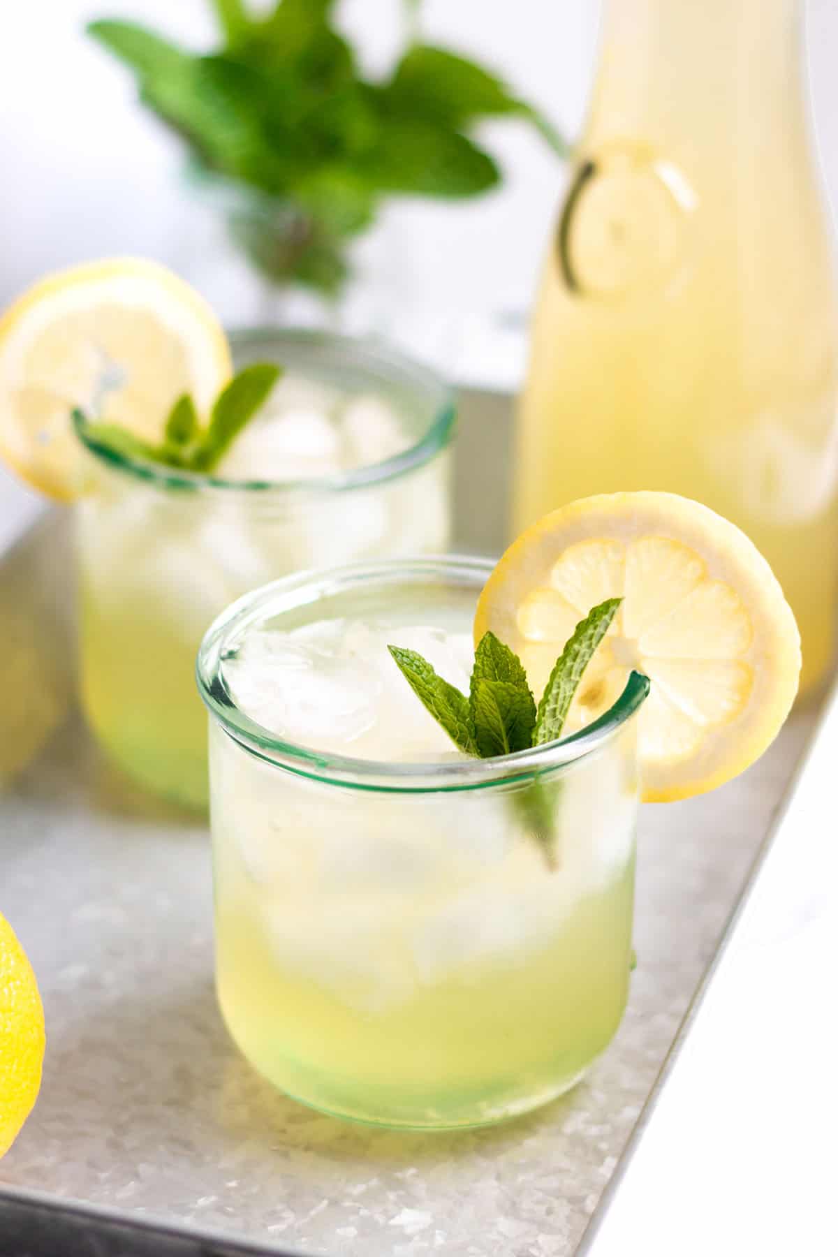 Two glasses with ice and lemonade with fresh mint and lemon slices.