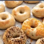 Baking sheet with homemade bagels topped with seeds and cheese.