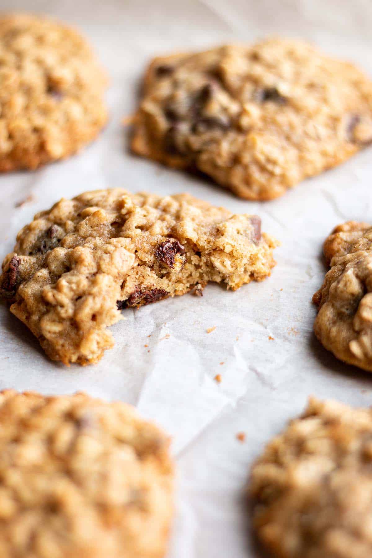 Oatmeal cookies on a baking sheet with one that has a bite taken out.
