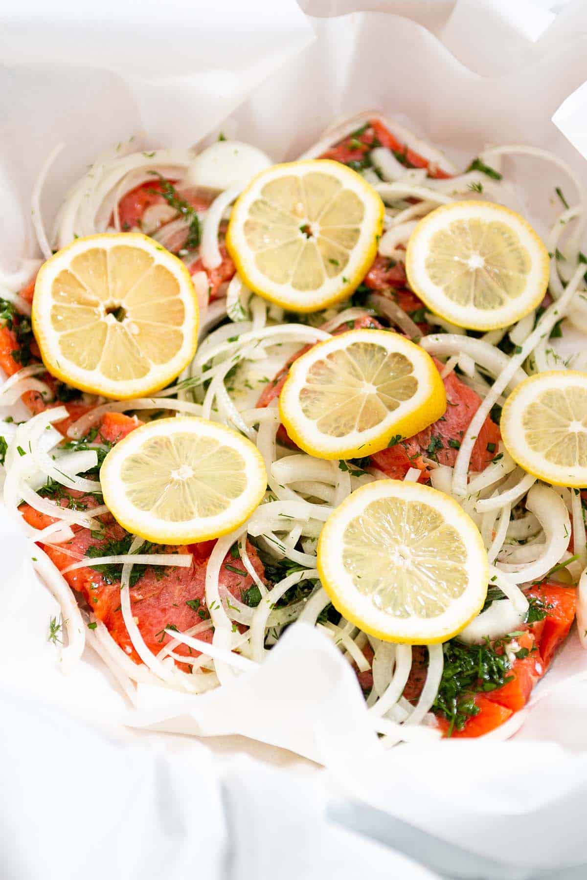 Parchment paper with salmon, onions and lemons slices.