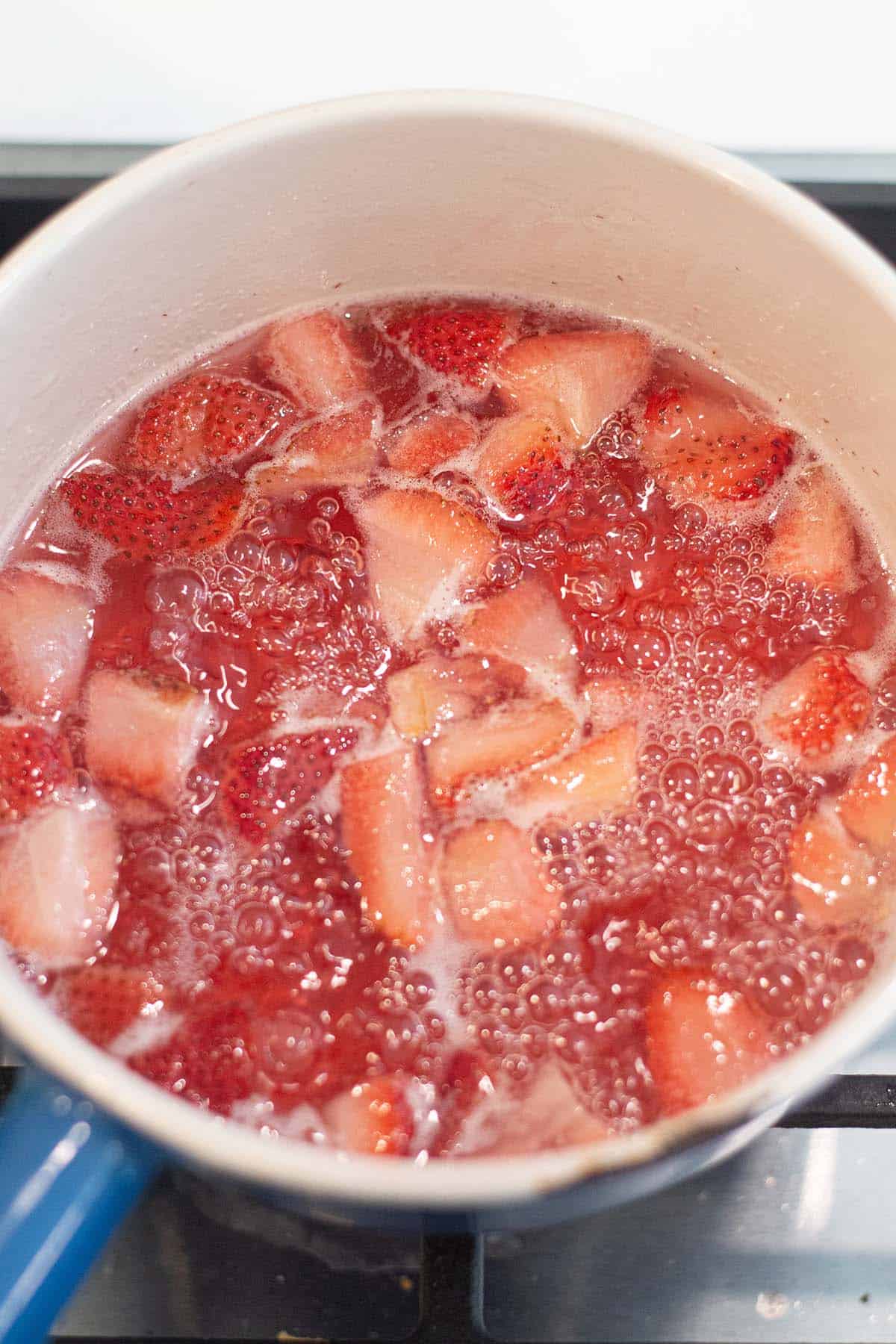 A small pot with strawberries boiling in water.