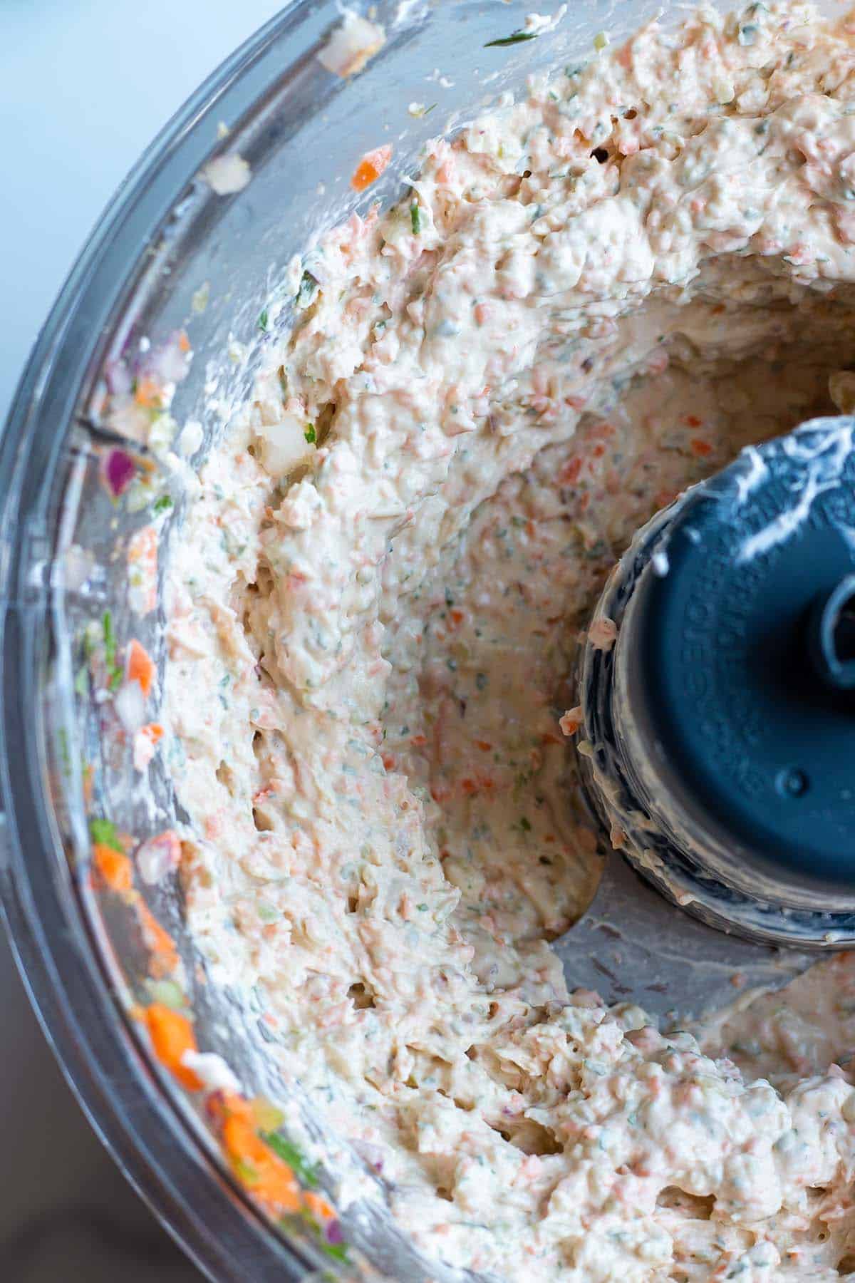 A food processor with cream cheese and diced veggies.