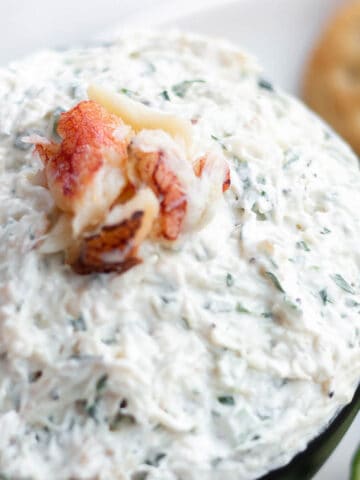 A bowl of fresh crab dip with cream cheese and a lump of fresh crab meat on top.