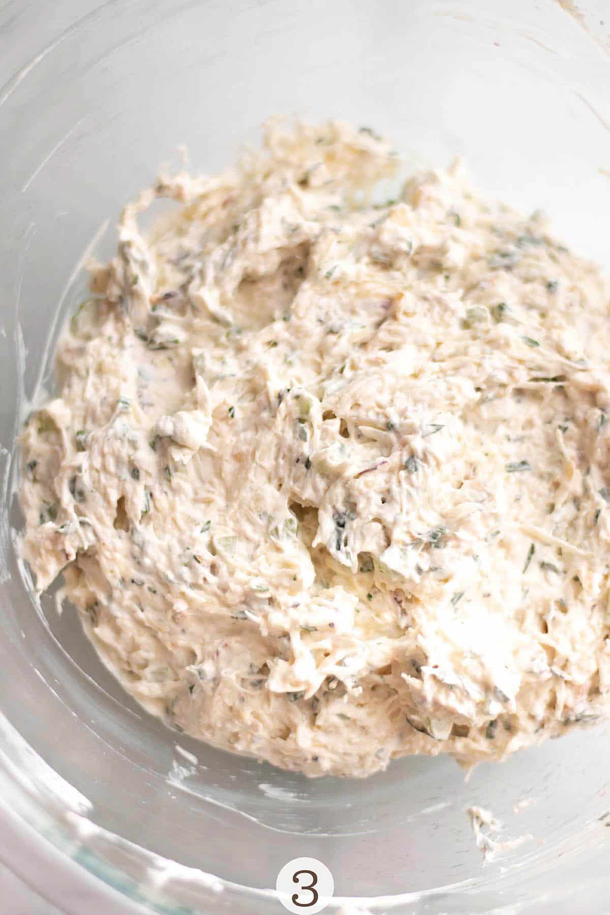 A glass bowl with cream cheese, sour cream and fresh crab mixed in.