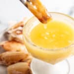 A piece of crab meat being dunked into a bowl of butter.