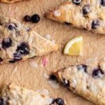 Blueberry scones on brown parchment with fresh lemon slices.