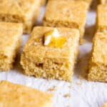 A piece of sourdough cornbread with some butter and honey on top.