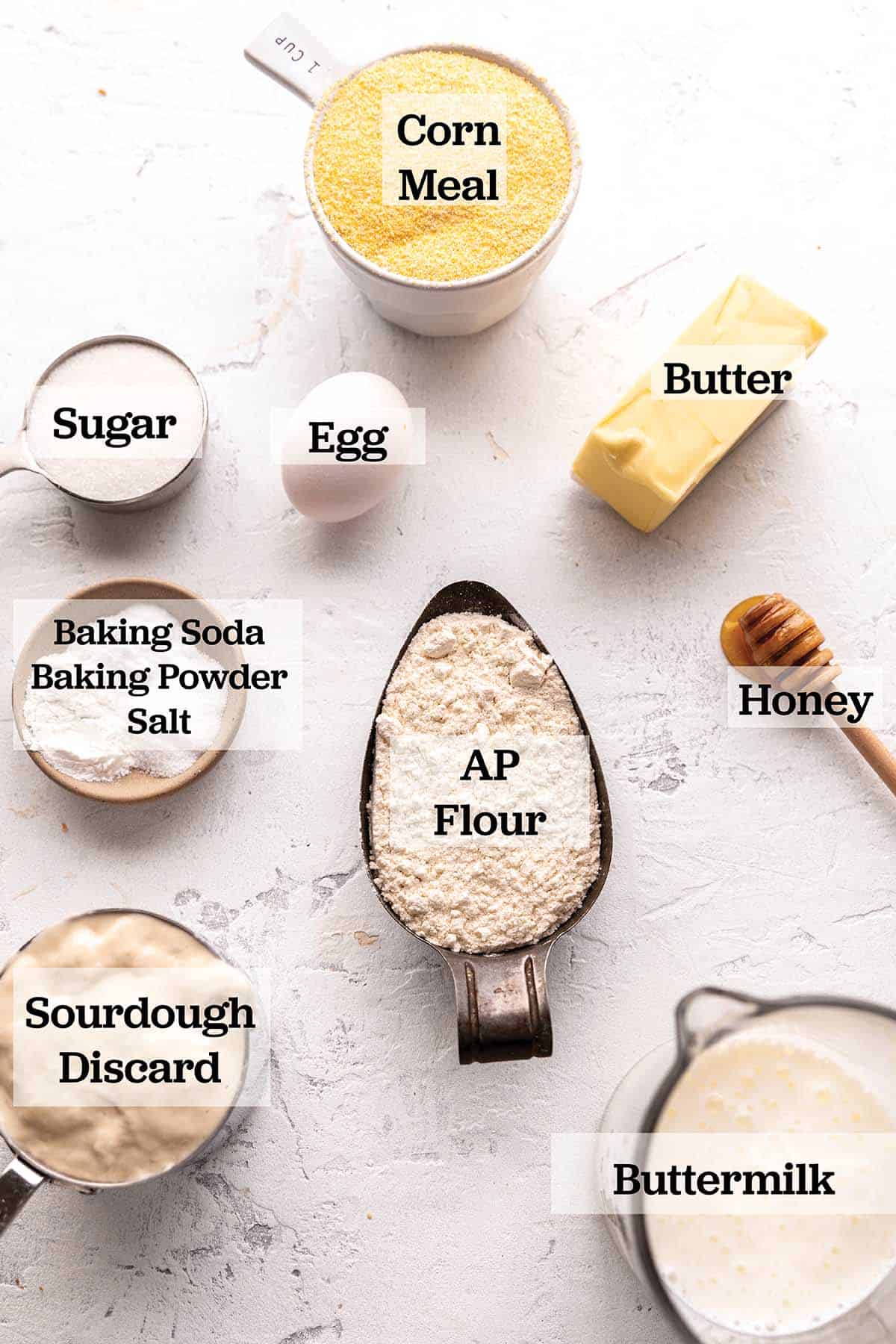 Ingredients measured out to make bread with cornmeal, flour, honey, sugar, egg, salt, and sourdough discard.