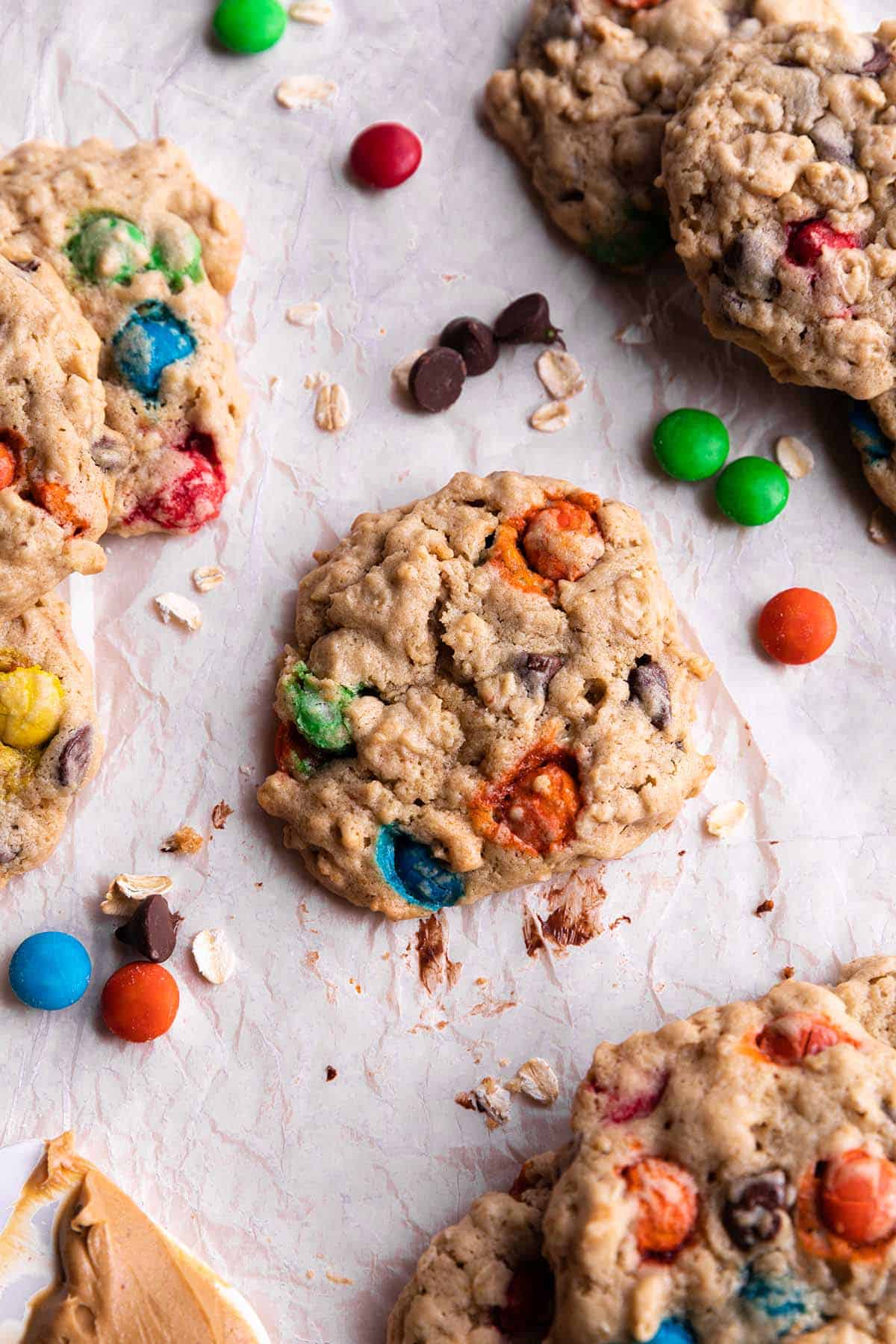 Cookies with oats, m&m's, chocoalte chips on parchment paper.