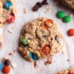 Oatmeal cookies with M&Ms, and chocolate chips on parchment paper.