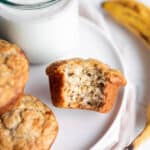 A plate with banana muffins and a glass of milk with a banana.